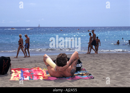 British vacanziere a prendere il sole sulla spiaggia a Playa de las Americas, Tenerife, Spagna Foto Stock