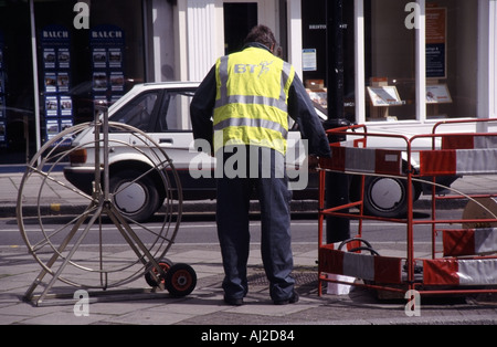 Chelmsford Essex BT lavoratore lavorando sul cavo la posa di lavoro accanto al marciapiede aperto tombino con barriere di sicurezza Foto Stock