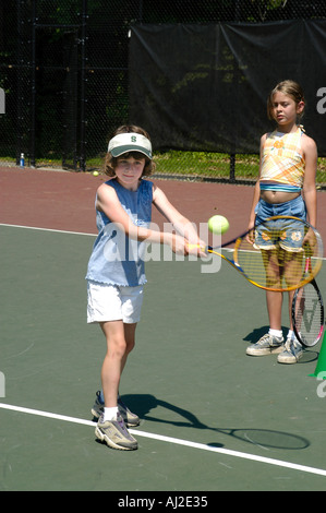 I ragazzi imparano a giocare a tennis presso il pubblico corte di ricreazione Foto Stock