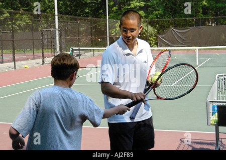 I ragazzi imparano a giocare a tennis presso il pubblico corte di ricreazione Foto Stock