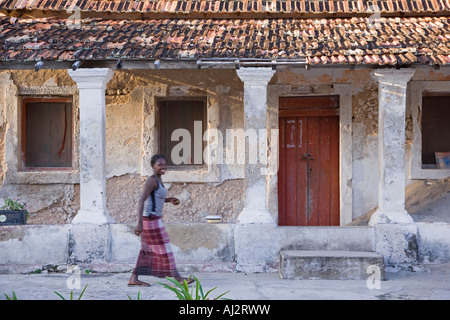 Una donna di fronte a una vecchia villa portoghese su ibo Island, parte dell'Arcipelago Quirimbas, Mozambico. Foto Stock
