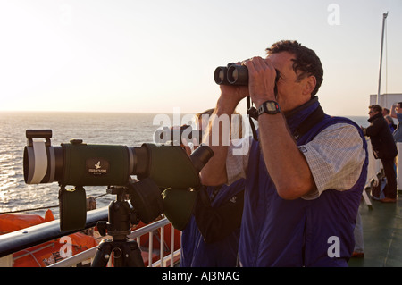 Primo piano di un uomo e di una donna a guardare il mare con un binocolo dalla nave Foto Stock