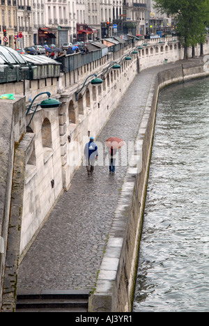 L uomo e la donna a piedi sotto la pioggia lungo la riva sinistra del fiume Senna a Parigi Francia Foto Stock