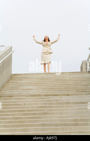 Imprenditrice a braccia alzate in alto di fasi Foto Stock