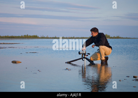 Fotografo in ginocchio in acque poco profonde del lago Michigan accanto alla fotocamera su treppiede vicino a Stonington Michigan Foto Stock