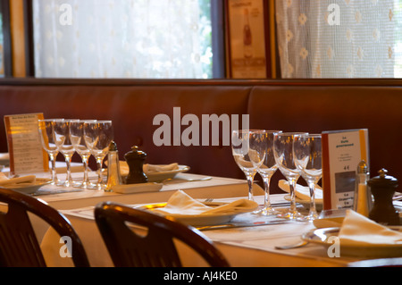 Il classico ristorante brasserie Bolingrin con set di tabelle con gli occhiali e la biancheria di tovaglioli e tovaglia, coltelli e forchette, shaker di sale e pepe, Reims, Champagne, Marne, Ardenne, Francia, bassa luce grano sgranate Foto Stock