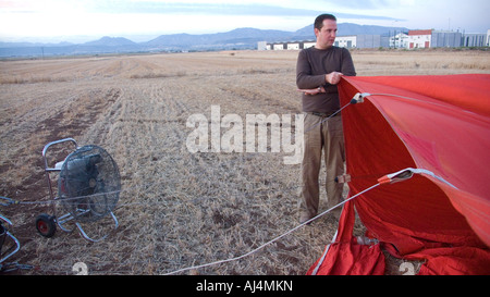 Il riempimento e il gonfiaggio del manto di una mongolfiera prima del volo in un campo di stoppie in Spagna Foto Stock