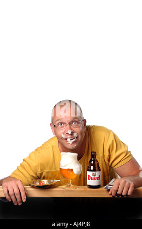 Uomo calvo in un bar a bere un freddo belga della birra duvel, mostrando schiuma intorno la sua bocca. Foto Stock