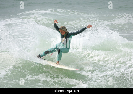 Una ragazza adolescente Surfer cavalca un'onda Foto Stock