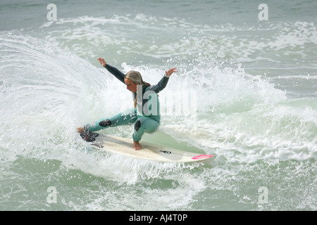 Una ragazza adolescente Surfer cavalca un'onda Foto Stock