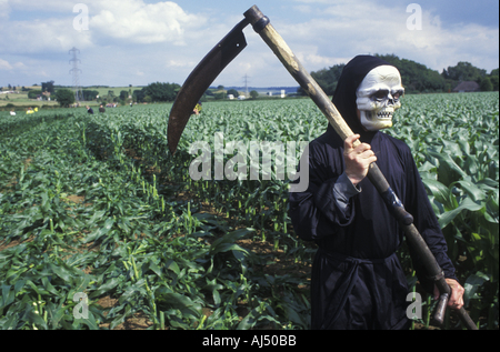 Un anti GM protester vestito come Grim Reaper fa il suo modo di un campo per abbattere il mais GM Foto Stock