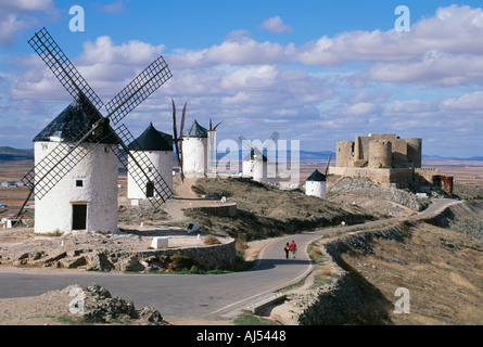 Mulini a vento e il castello che domina la pianura di Castilla La Mancha Spagna giovane camminare insieme. Viaggiare in Spagna turismo cultura Foto Stock