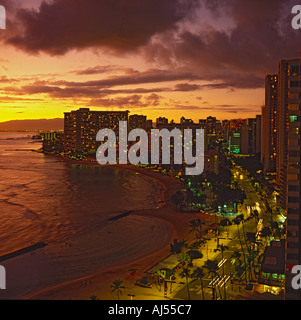 Vista lungo la curvatura centrale di Waikiki Beach e grigio violazione del litorale al tramonto Honolulu Oahu Island Hawaii Foto Stock