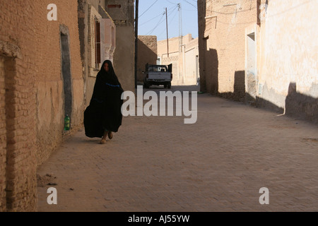 Donna locale a piedi nel quartiere vecchio di Tozeur Ouled El Hedef Foto Stock