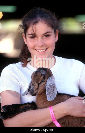 Ritratto di donna sorridente adolescente abbracciando vincitore del premio per capra a County Fair Foto Stock