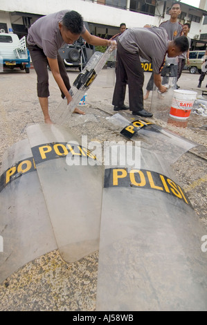 Indonesiano degli ufficiali di polizia lavando loro i anti-sommossa scudi a loro centrale composto di Jayapura, Indonesia. Foto Stock