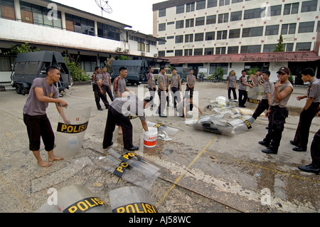 Indonesiano degli ufficiali di polizia lavando loro i anti-sommossa scudi a loro centrale composto di Jayapura, Indonesia. Foto Stock