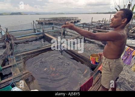 Ritratto di un uomo di Papua alimentando il suo stock di pesca, vicino alla sua casa sul lago Sentani, Jayapura, Indonesia. Foto Stock