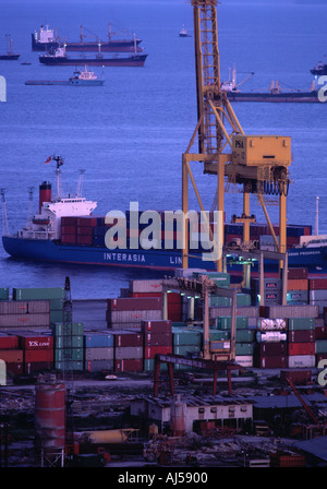 Contenitori essendo caricato con una gru giganti sulle navi in porto di Singapore Foto Stock