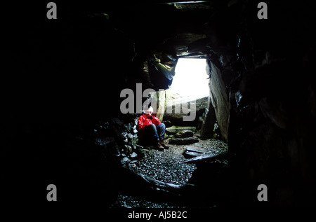 Persona seduta all'interno del Nether Largie South Chambered Cairn Foto Stock