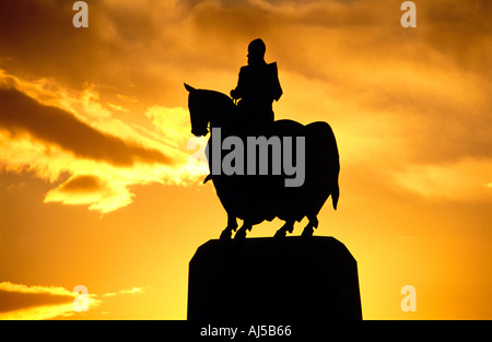 Statua equestre di Robert the Bruce stagliano da una vivida golden orange sky dal tramonto. Foto Stock