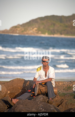 L'uomo suonando la batteria nella luce della sera dalla principale spiaggia della Baia di Byron New South Wales NSW Australia Foto Stock