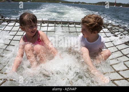 Ragazzo e ragazza ridere i bambini a giocare in acqua di nave da crociera boom net Port Stephens New South Wales NSW Australia NAOH Foto Stock