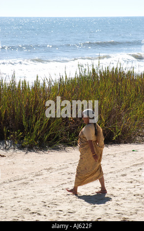 Donna mediorientale in un abito giallo che cammina lungo la costa di Myrtle Beach, South Carolina, Stati Uniti. Foto Stock