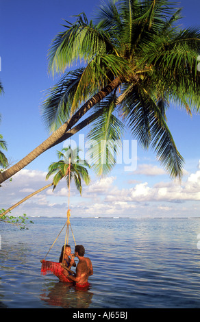 Paio di condivisione drink tropicali in altalena appesi da Palm tree su Meeru Island delle Maldive Foto Stock