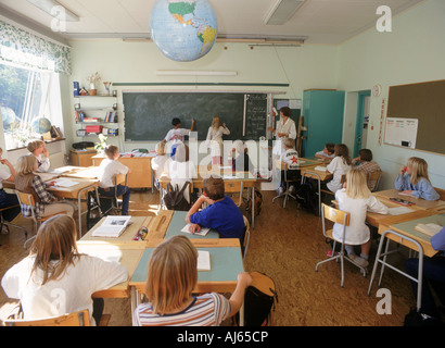 I bambini delle elementari a banchi e lavagna in aula svedese di seguito Globo mondo Foto Stock