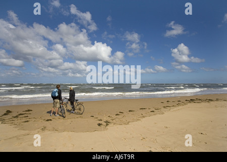 Un paio di giovani ciclisti prendere un periodo di riposo sulla spiaggia Holkham Norfolk e ammirare la vista Foto Stock