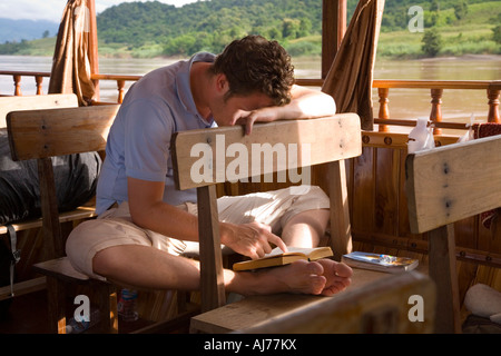 Lettura passeggero sulla barca lenta tra Luang Prabang e Huay Xai sul fiume Mekong in Laos Foto Stock