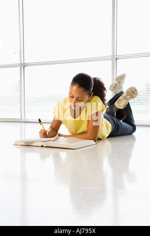 African American Girl giacente sul piano facendo lavori scolastici Foto Stock