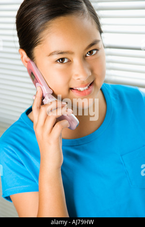 Asian preteen girl parlando al cellulare e guardando il viewer Foto Stock