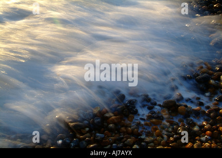 Ondata di schiantarsi su stoney beach con una lenta velocità otturatore Foto Stock