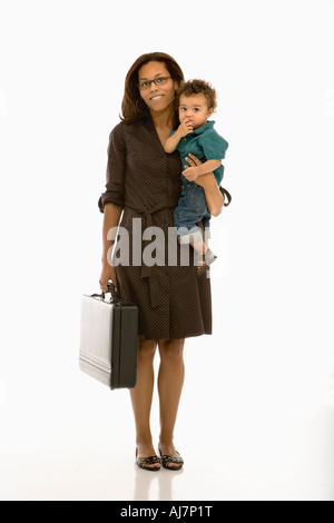 African American metà adulto imprenditrice azienda toddler figlio sulla hip sorridente al viewer Foto Stock