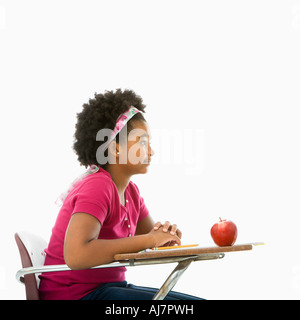 Vista laterale del americano africano ragazza seduta nel banco di scuola Foto Stock