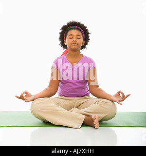Americano africano ragazza seduta sul pavimento in yoga lotus postura con gli occhi chiusi Foto Stock