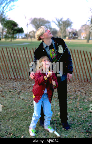 Cugini età 16 e 7 aquilone volante a Pasqua incontro di famiglia. Vittoria Memorial Drive Minneapolis Minnesota USA Foto Stock