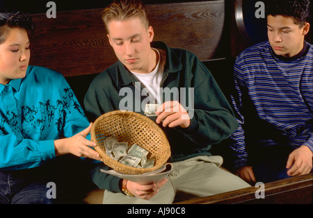 Il coreano American Girl Età 15 passando chiesa offrendo cesto al ragazzo età 16. St Paul Minnesota USA Foto Stock