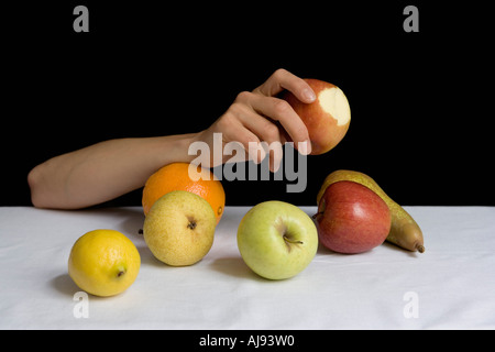 Braccio appoggiato sulla tavola tra la frutta Foto Stock