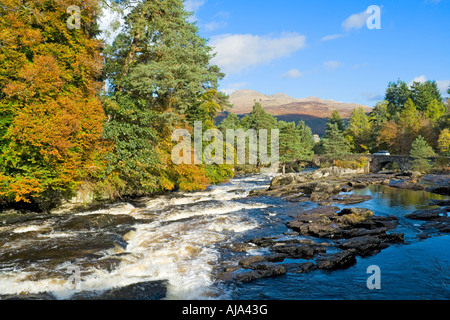 Più piccole cascate sul fiume Dochart a Killin con il fiume Dochart Bridge e parte della cresta Tarmachan dietro Foto Stock