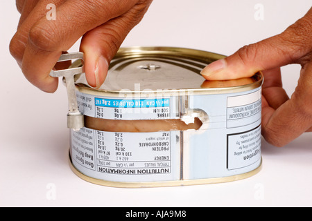 Donna di aprire una lattina di maiale con una chiave Foto Stock