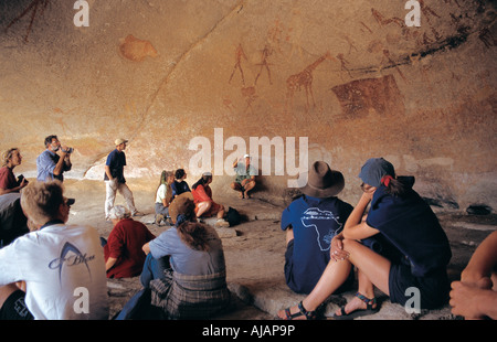 Guida Ian Harmer dà lezione sui dipinti dei Boscimani all'interno di una grotta in Matobo Parco Nazionale dello Zimbabwe Foto Stock