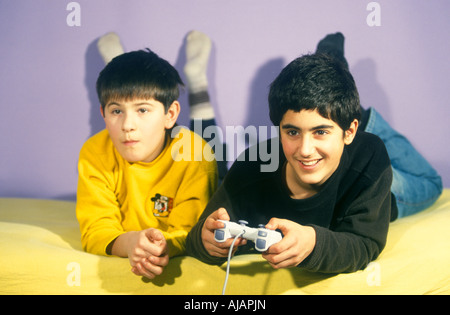 Un giovane ragazzo giocando a un gioco per computer mentre il suo amico sta guardando Foto Stock