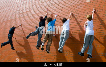 Cinque ragazzi adolescenti salta contro un muro come essi eseguire parkour maneouvres Foto Stock