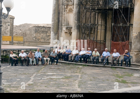 Persone locali seduti davanti alla Chiesa Madre a Ferla Foto Stock