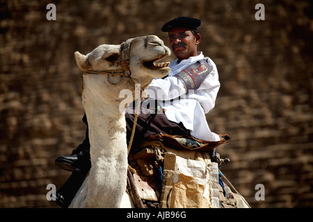 Turismo egiziano poliziotto polizia seduto su un cammello guardia piramidi complesso con la Grande Piramide di Cheope Khufu al di là di Giza C Foto Stock