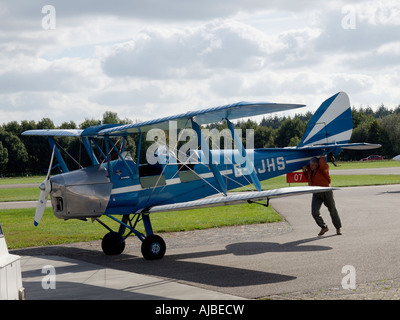 Uomo che si muove il suo classico tiger moth velivolo biplano con potenza muscolare solo seppe airfield nei Paesi Bassi Foto Stock