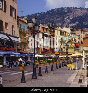 Vista lungo il lungomare di ristoranti edifici e città salendo una collina al di là a Villefranche-sur-Mer Francia Foto Stock